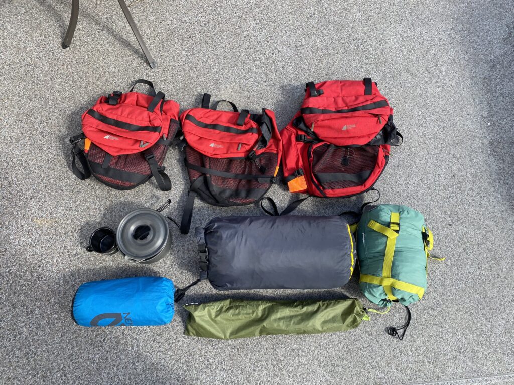 A pile of colourful camping gear is laid out in an organized manner. The photo is taken from a bird's eye view.